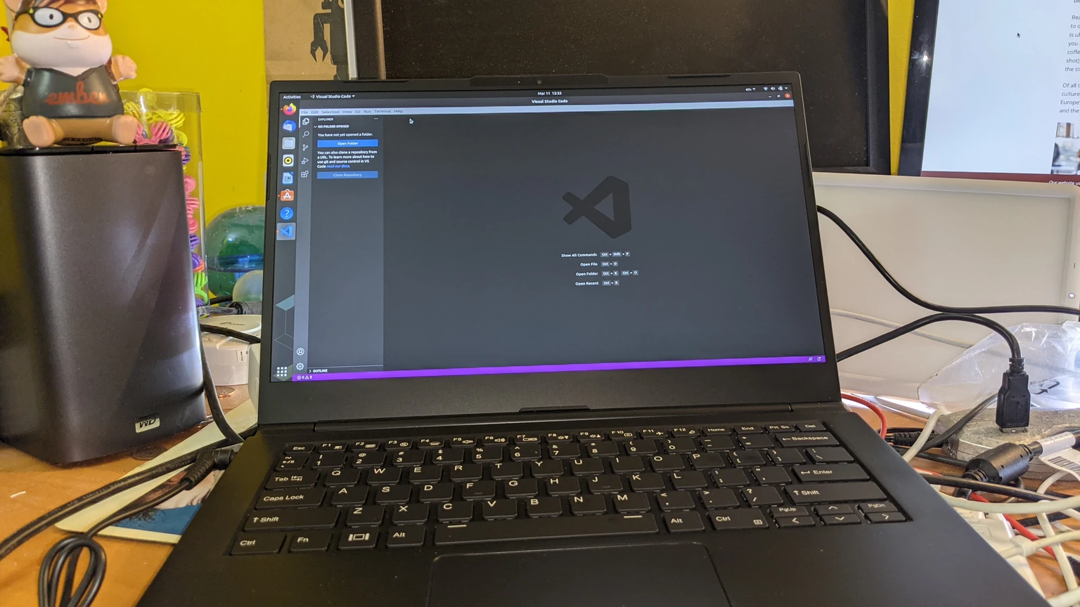 An open black laptop on a desk showing Visual Studio Code on an Ubuntu desktop. No people appear.