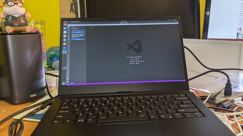 An open black laptop on a desk showing Visual Studio Code on an Ubuntu desktop. No people appear.