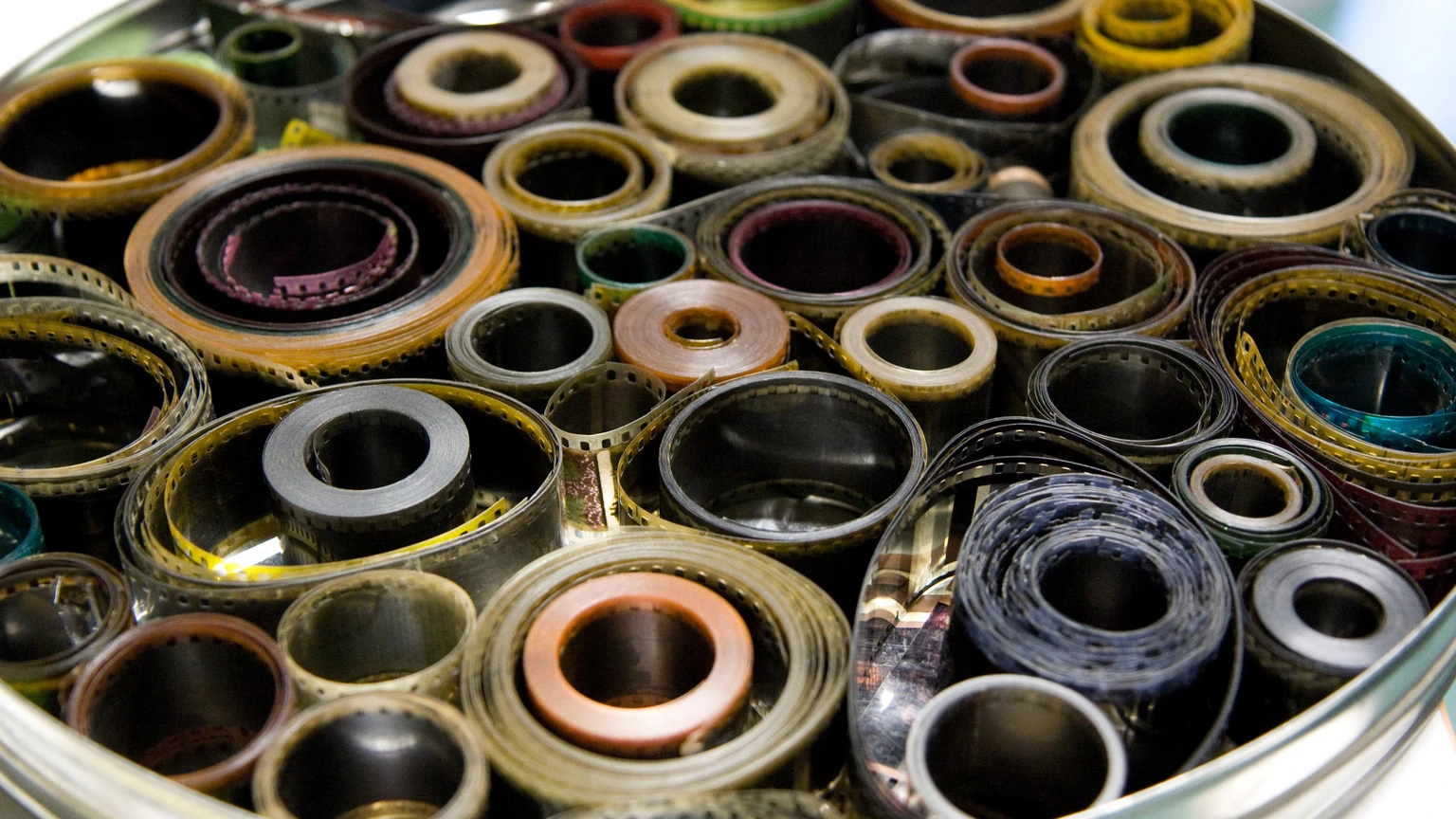 A round metal tin packed with coiled celluloid film rolls. No people appear.