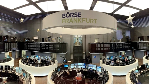 Wide exterior view of the Frankfurt Stock Exchange building with its classical facade under a bright sky. No people are identifiable as subjects.