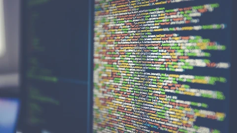 Close-up of a computer monitor filled with colourful lines of JavaScript code, slightly out of focus at the edges.