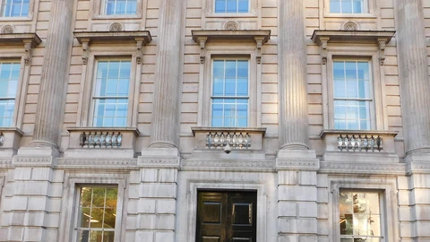 Pale stone facade of the Cabinet Office at 70 Whitehall in London, with tall sash windows, carved balconies and a black front door.