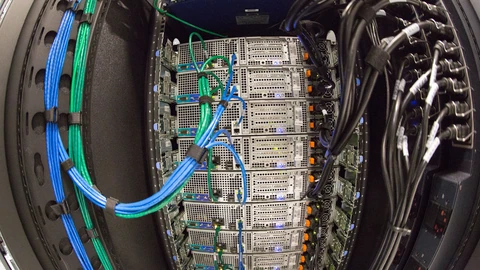 Fisheye view inside an open server rack: a column of stacked servers with blue and green network cables bundled down the left and black power cables down the right.