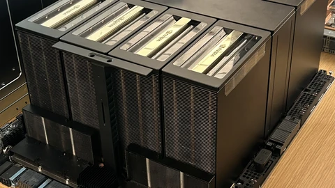 A black NVIDIA HGX B200 server board on a display table, with eight tall finned GPU heatsinks arranged in two rows and a small placard behind them.