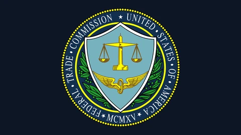 The round seal of the US Federal Trade Commission: a pale blue shield with golden scales of justice above a winged wheel, framed by green laurel branches and a dark blue ring reading Federal Trade Commission, United States of America, MCMXV, centred on a plain dark navy background.