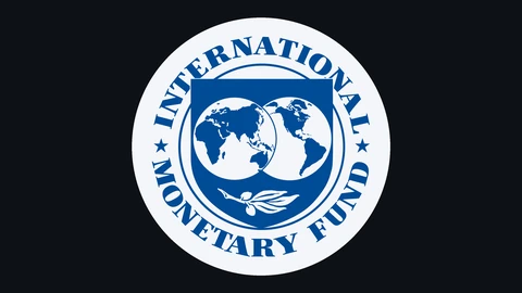 The blue seal of the International Monetary Fund, two globes inside a shield with an olive branch and the words International Monetary Fund around the rim, on a pale disc against a near-black background.