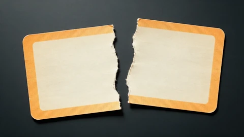 AI-generated illustration of a blank orange-and-cream paper rail ticket torn into two pieces on a dark charcoal background.