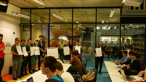 Hackathon participants comparing project ideas beside presentation boards.