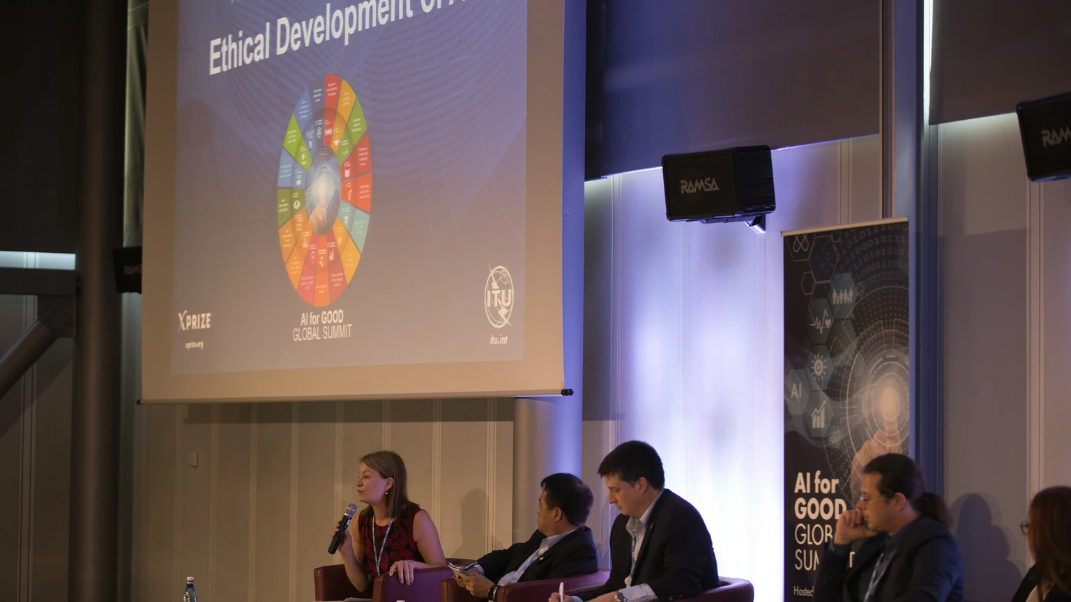 An AI ethics panel seated beneath a presentation screen.