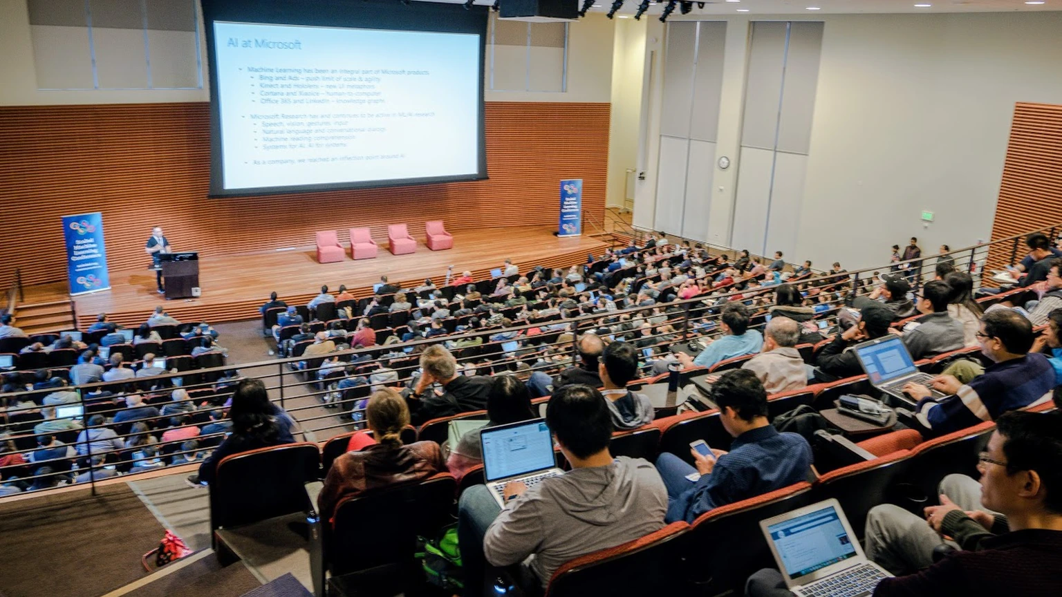 An audience seated in an auditorium at a machine learning conference.