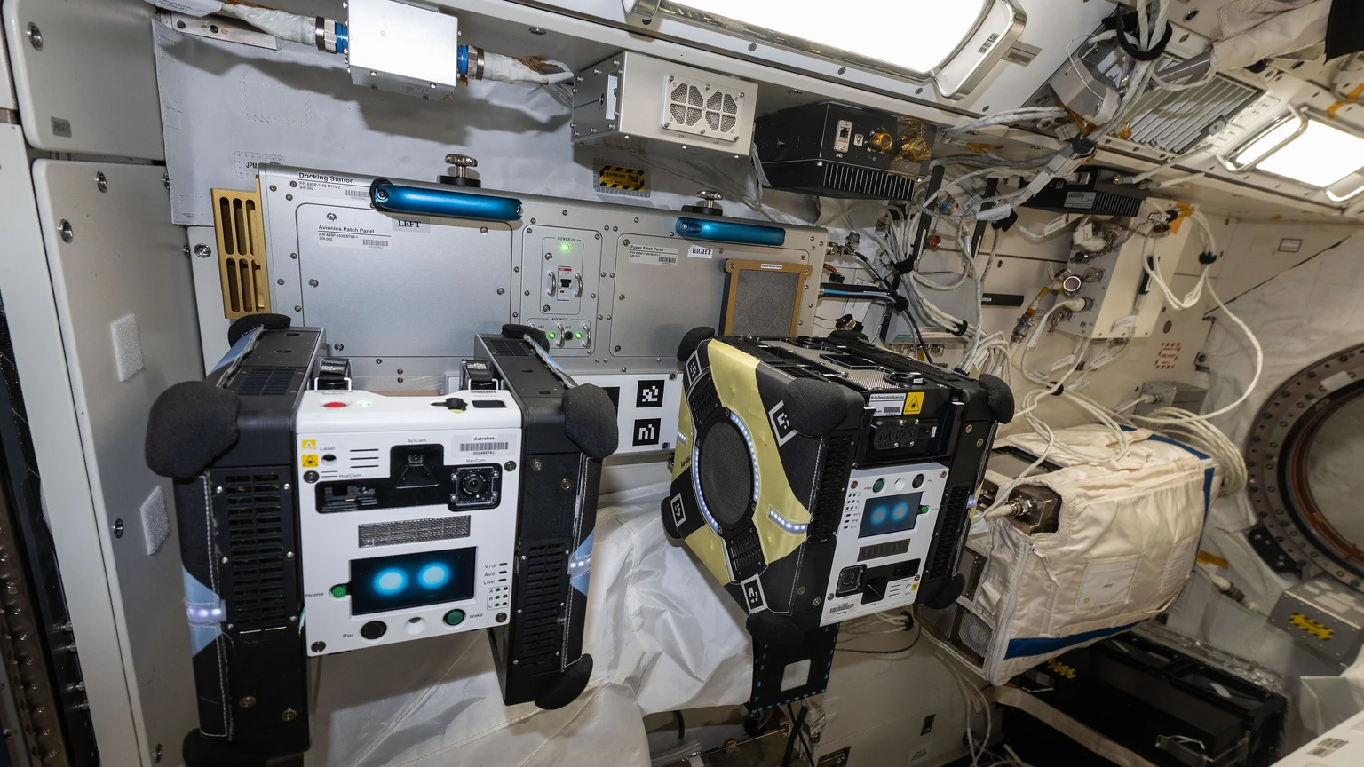 Two Astrobee robots docked inside the International Space Station Kibo laboratory.