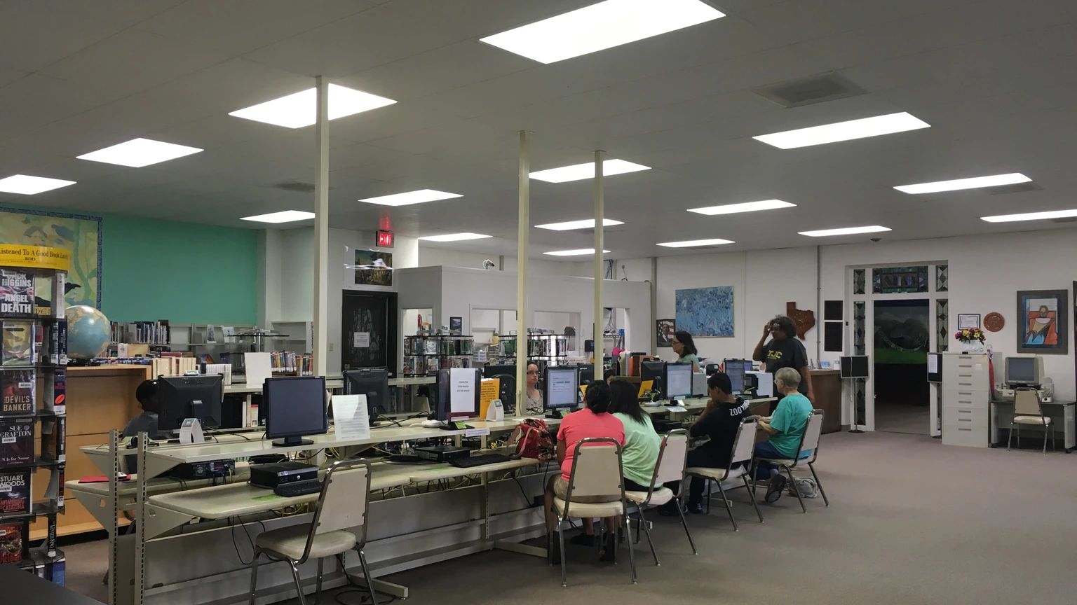Library visitors using computers in the bright computer area of Cuero Public Library.